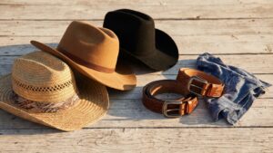 Cowboy hats and coiled tooled western belts arranged on weathered barn wood in golden light